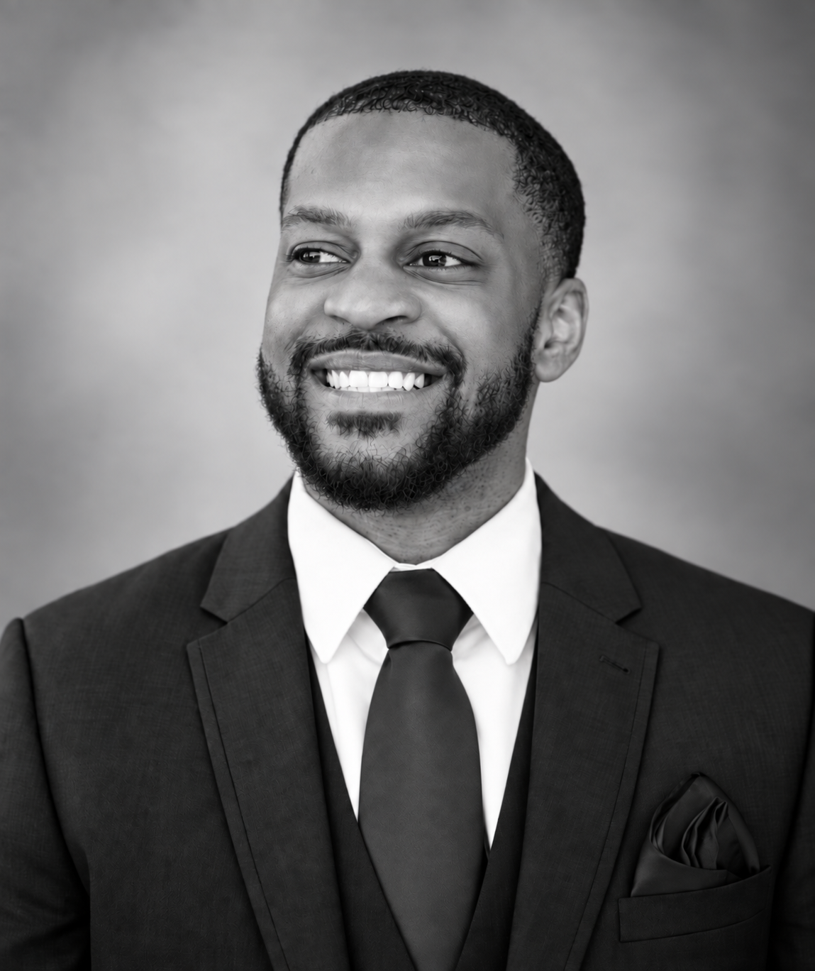 Elijah Burgess smiling in a black suit and tie